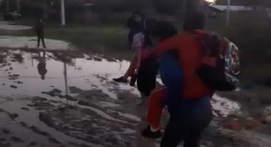 Puerto Casado: madres cargan a sus hijos para cruzar calle inundada